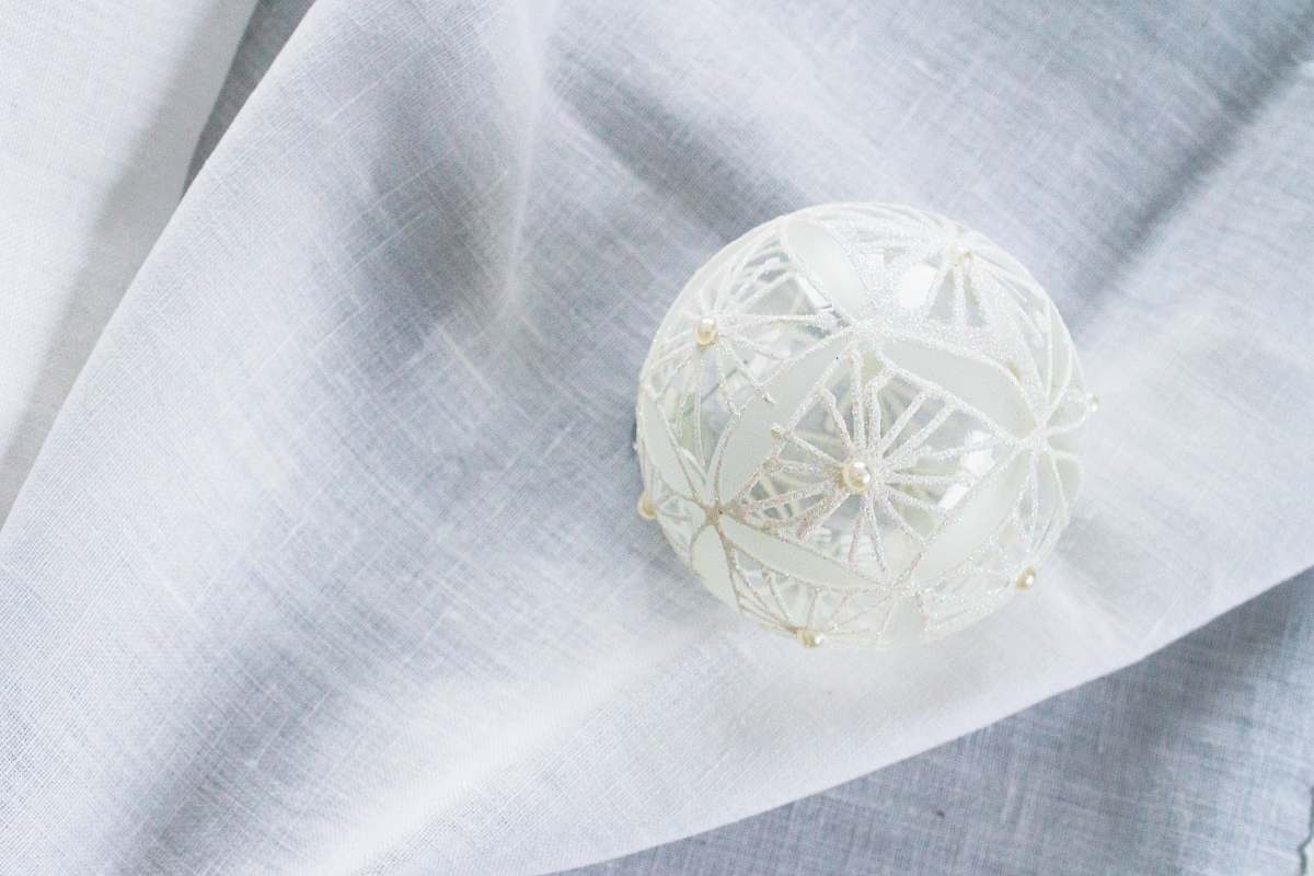 home decor white lace Christmas bauble on white garment linen